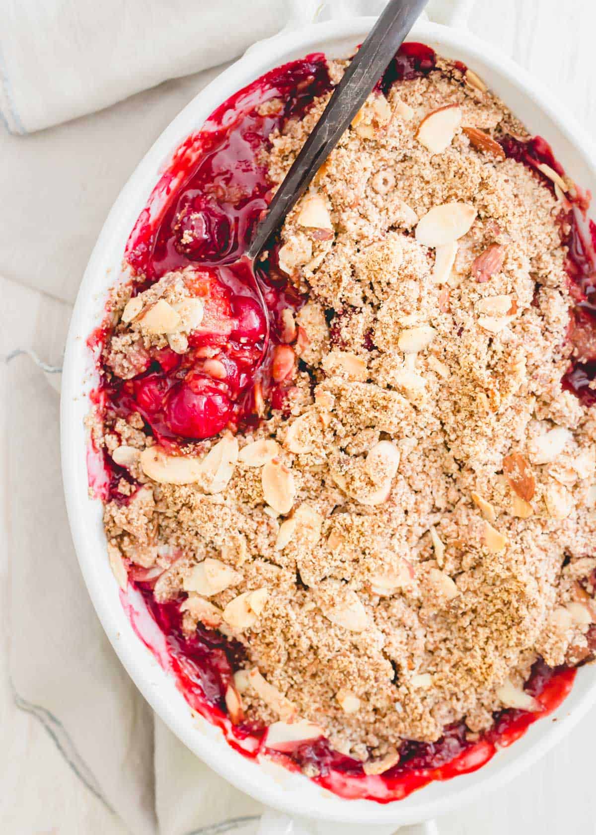 Baked tart cherry crisp with a spoonful being scooped out to serve.