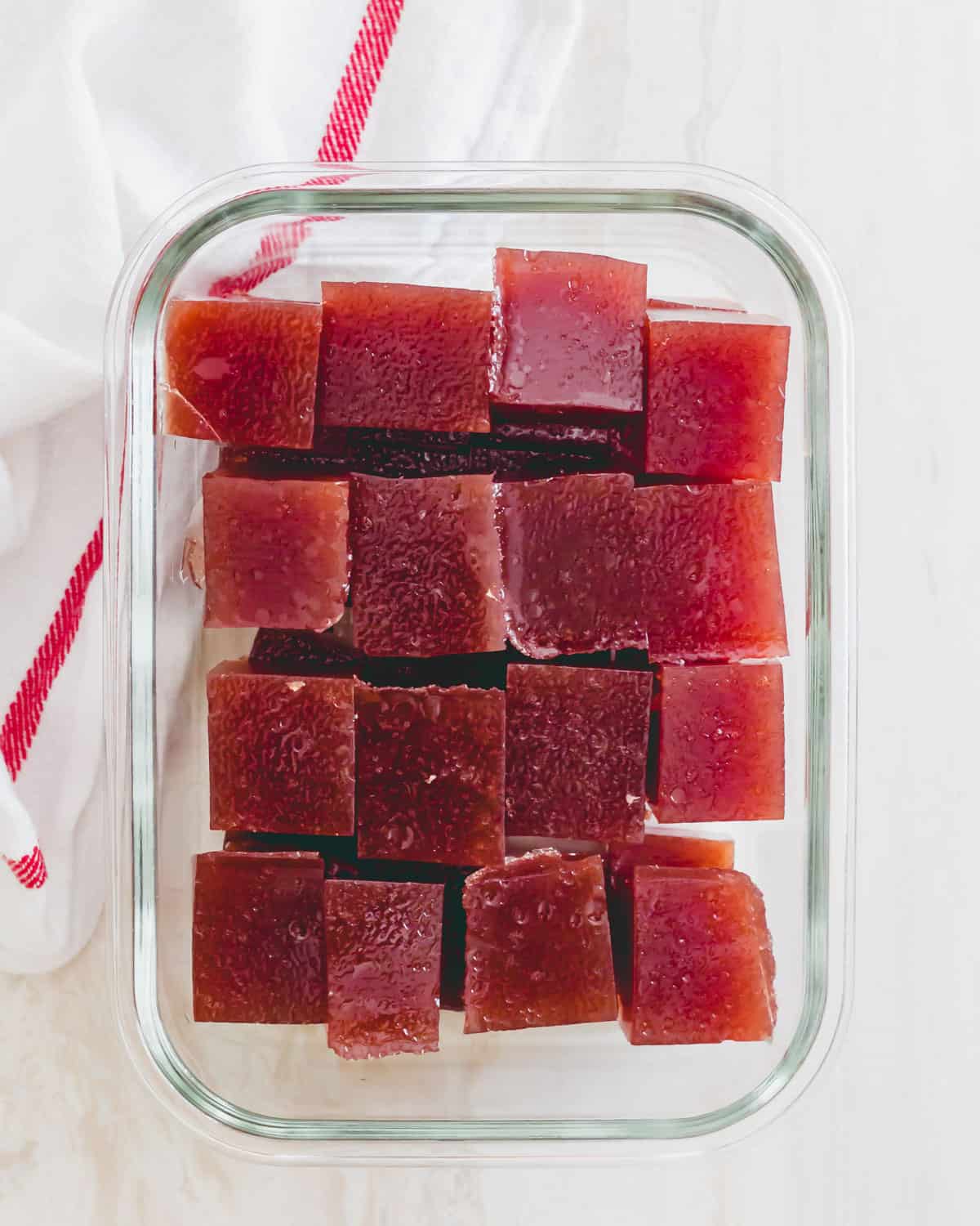 Tart cherry gummies cut into squares in a glass container for nighttime use.