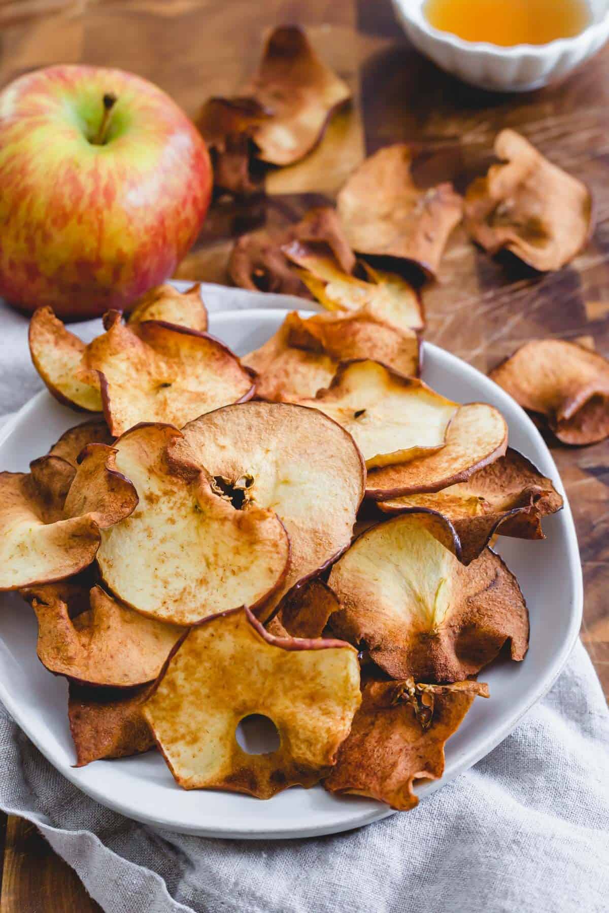 Easy maple cinnamon air fryer apple chips on a plate.