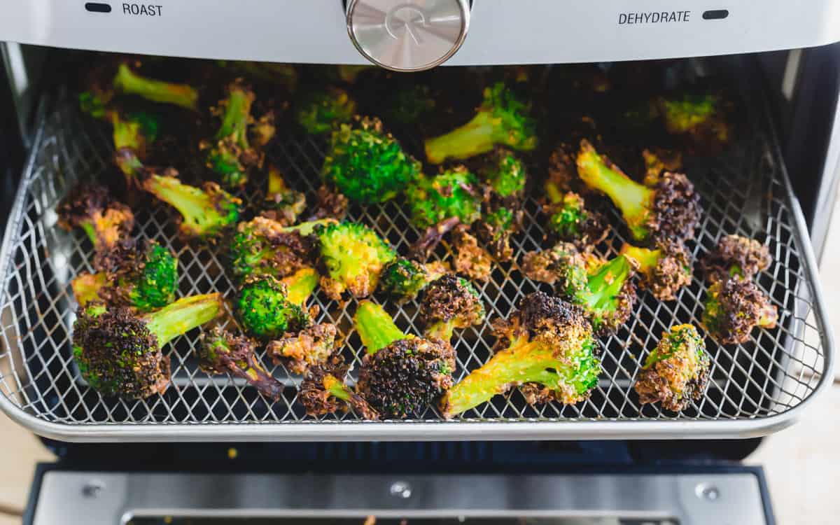 Air fried frozen broccoli on the tray in the air fryer.