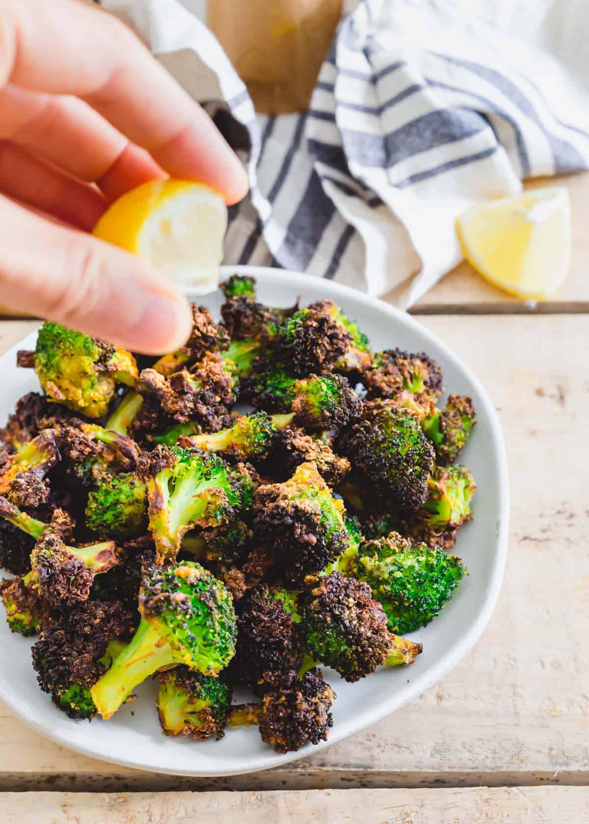 Squeezing lemon over air fryer frozen broccoli florets.