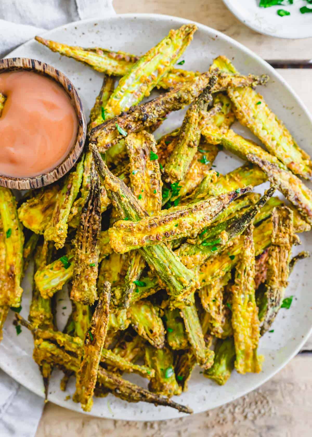 Crispy crunchy air fryer okra on a plate with dipping sauce.