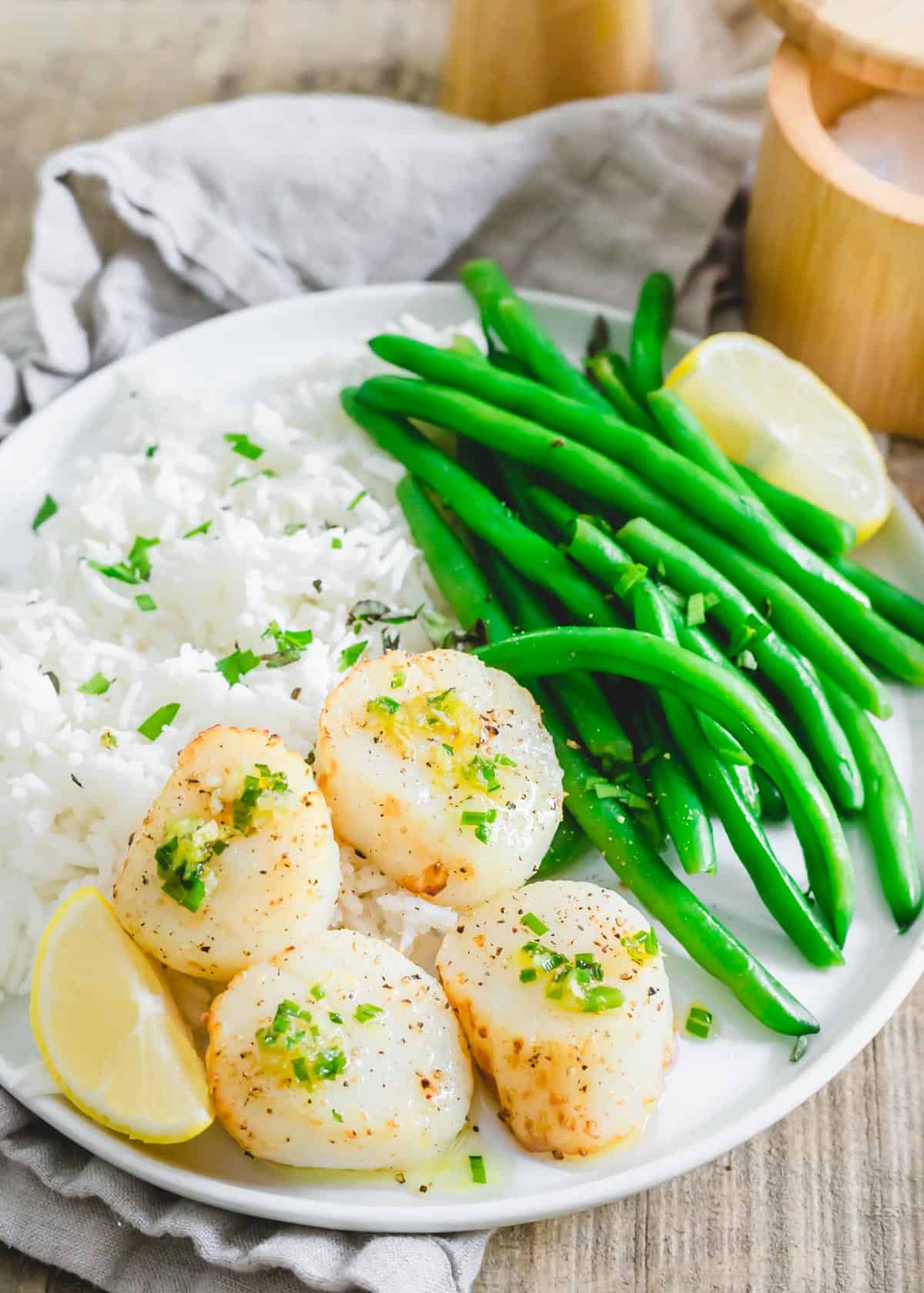 Perfectly cooked air fryer scallops with a chive garlic lemon butter sauce on a plate.