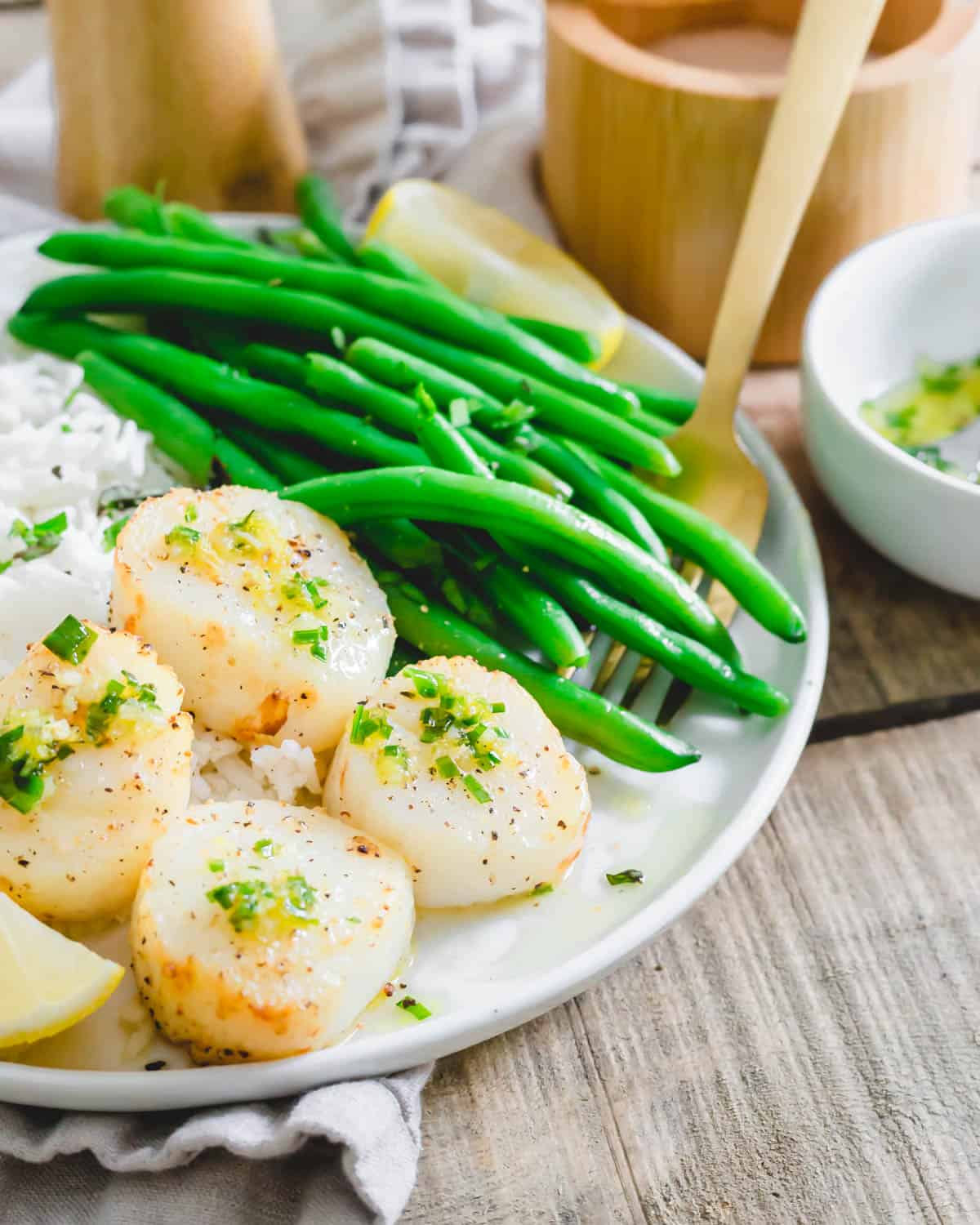 Perfectly tender air fryer scallops on a plate with green beans and rice.