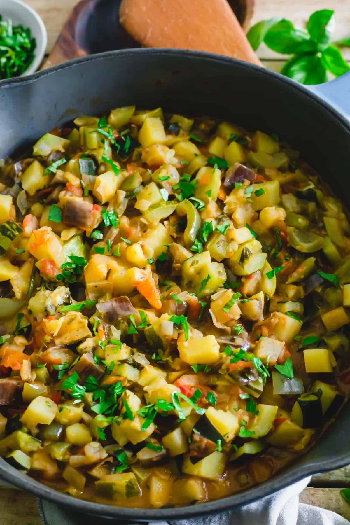 Ciambotta with eggplant, potatoes, onions, tomatoes, zucchini and peppers in a pot.