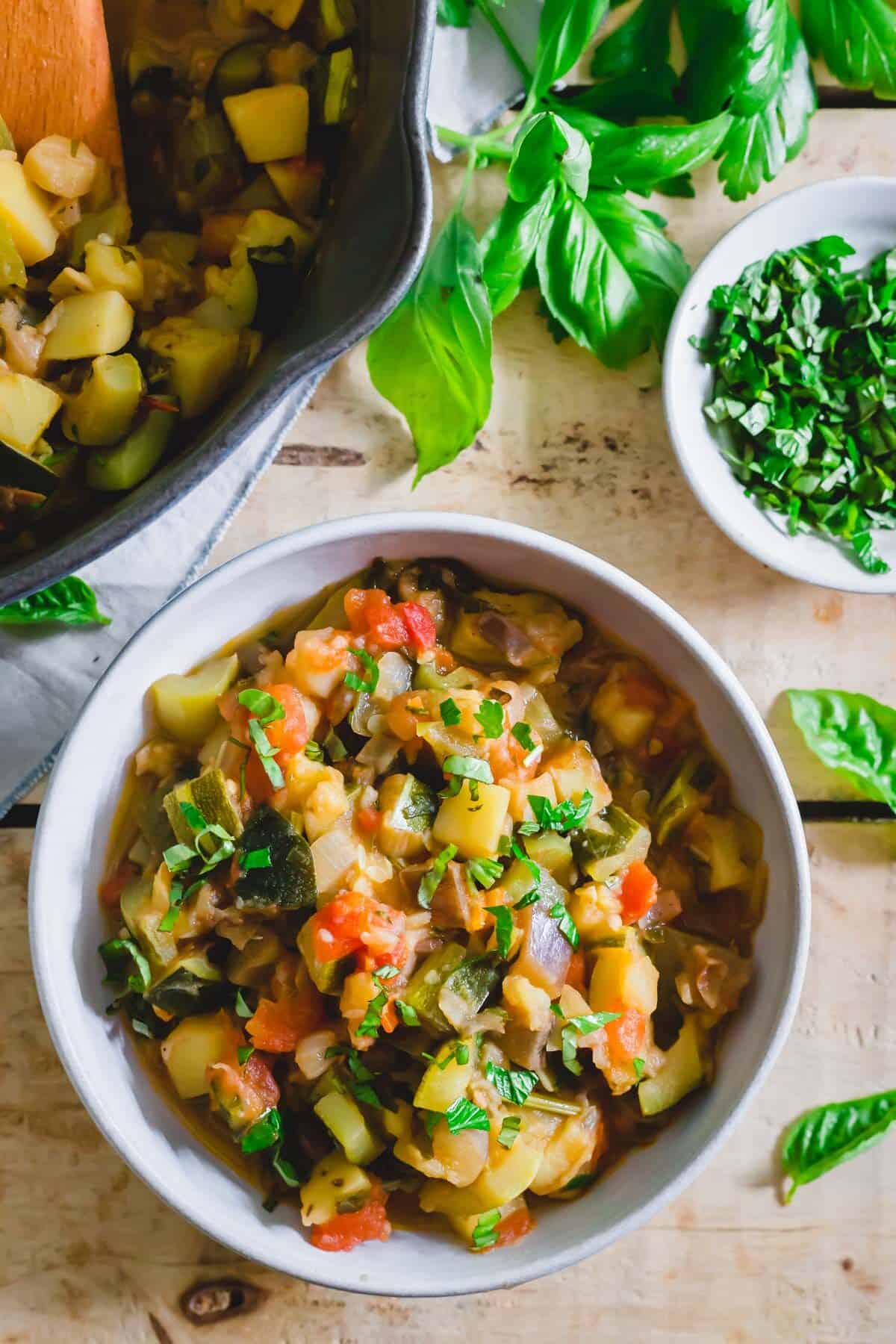 Italian ratatouille known as ciambotta in a bowl with fresh basil for serving.