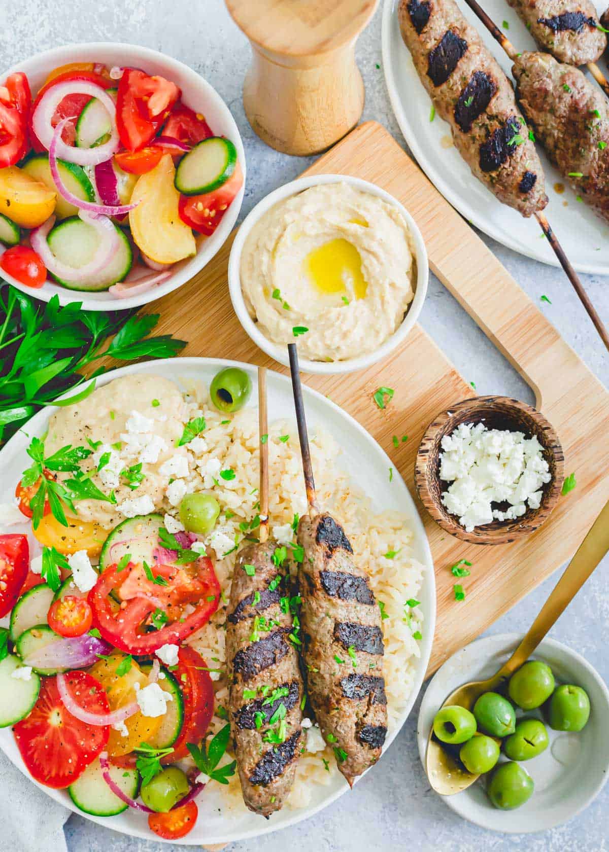 Easy beef kafta recipe on a plate with brown rice, feta, hummus, olives and a tomato cucumber salad.