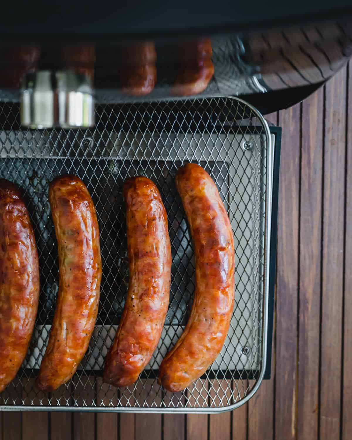 Juicy air fryer brats on the air fryer tray.