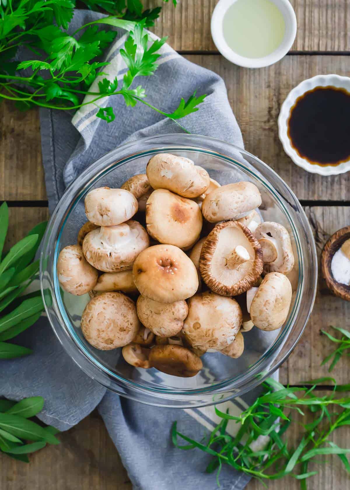 Raw baby portobello and shiitake mushrooms in a bowl before air frying.