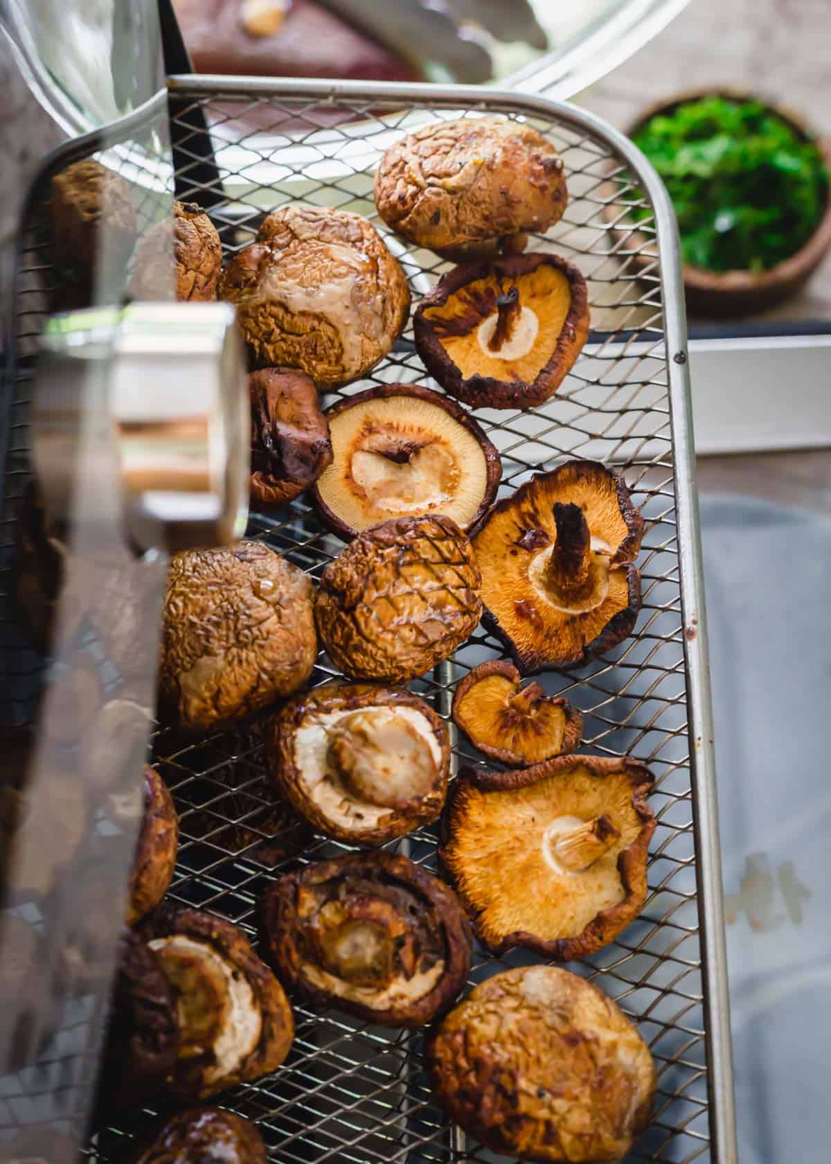 Whole roasted air fried mushrooms on the tray in the air fryer.