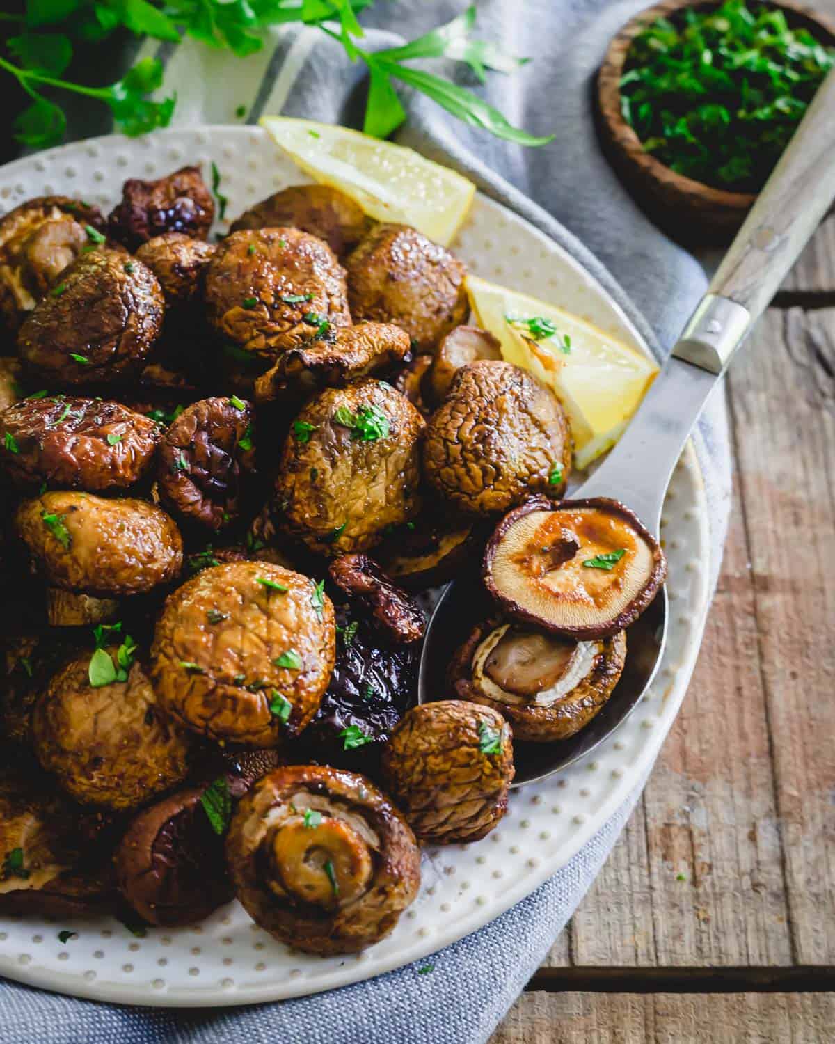 Garlic tamari seasoned whole air fryer mushrooms on a serving spoon.