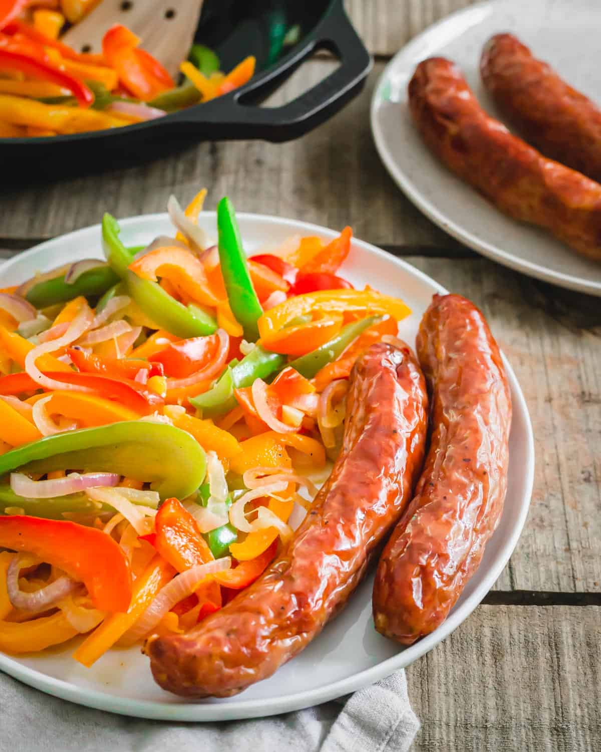 Air fryer Italian sausage served with peppers and onions on a plate.