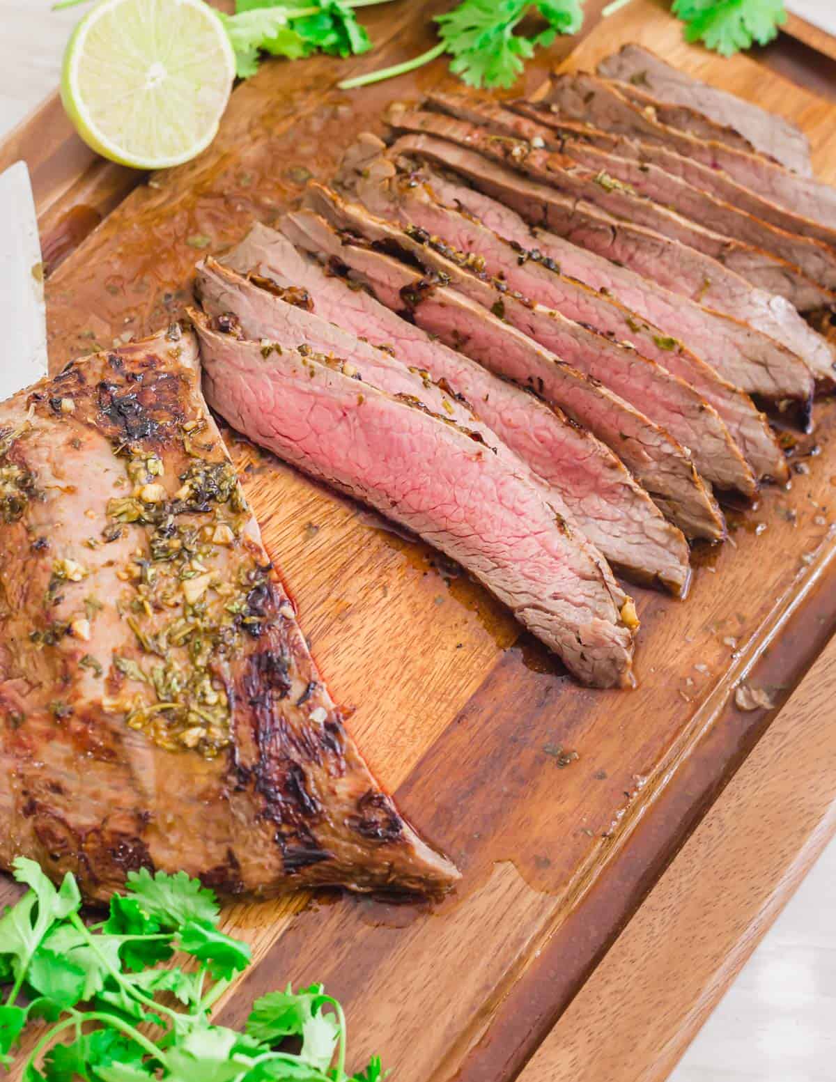 Grilled carne asada flank steak sliced on a cutting board.