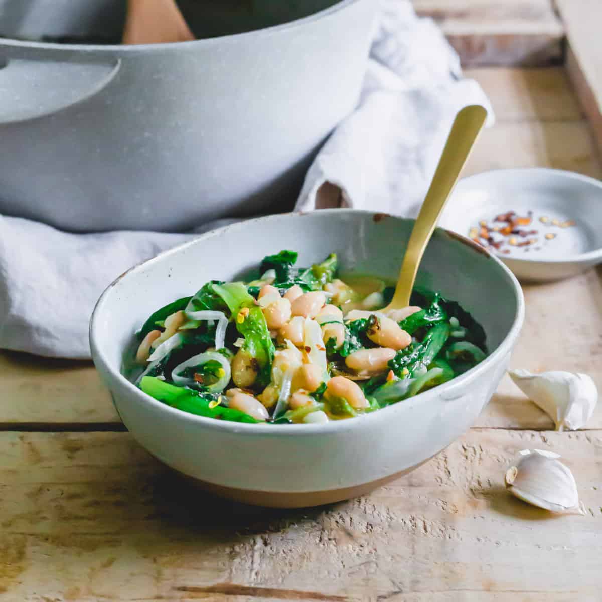 Escarole and bean soup in a serving bowl with a spoon.