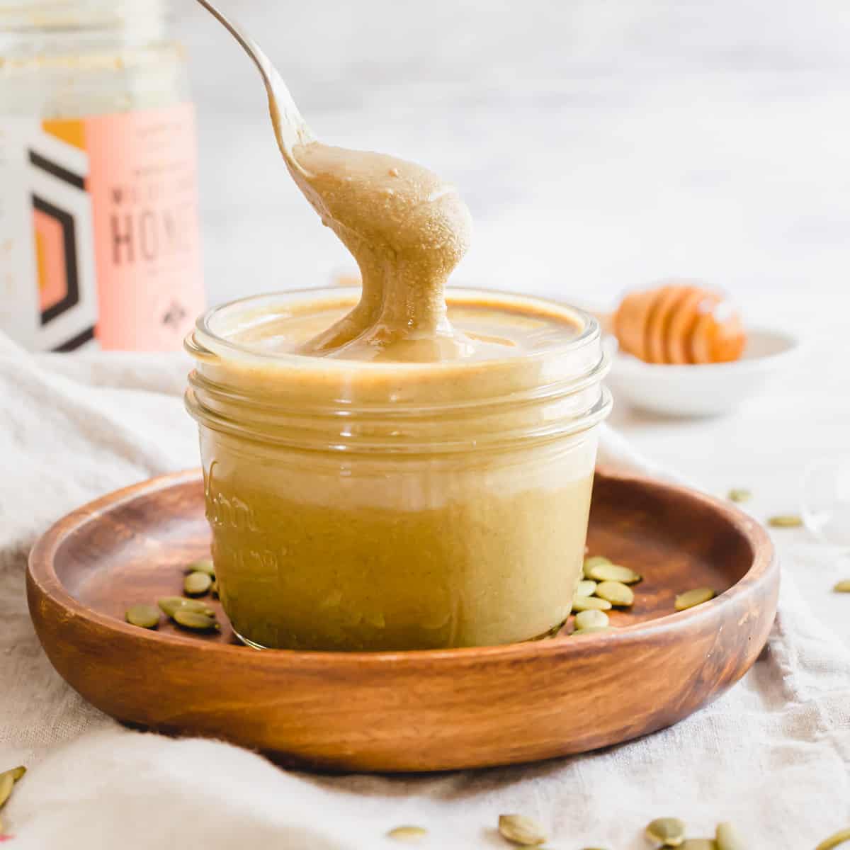 Creamy pumpkin seed nut butter recipe in a jar with a spoon.
