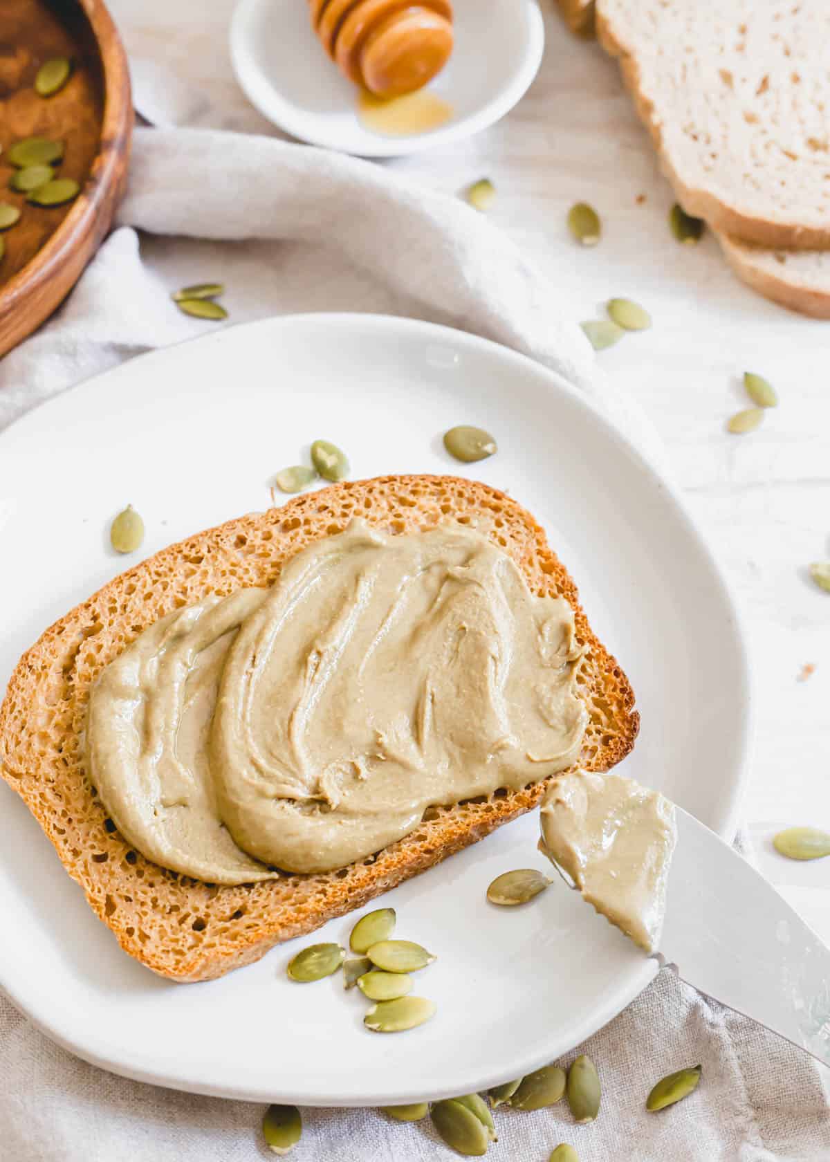 Spreading healthy pumpkin seed butter on gluten-free sourdough toast.