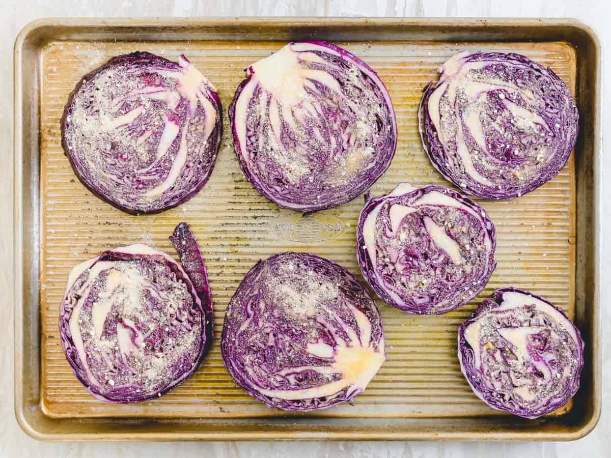 Red cabbage steaks seasoned with garlic, onion powder and salt on a baking sheet to be air fried.