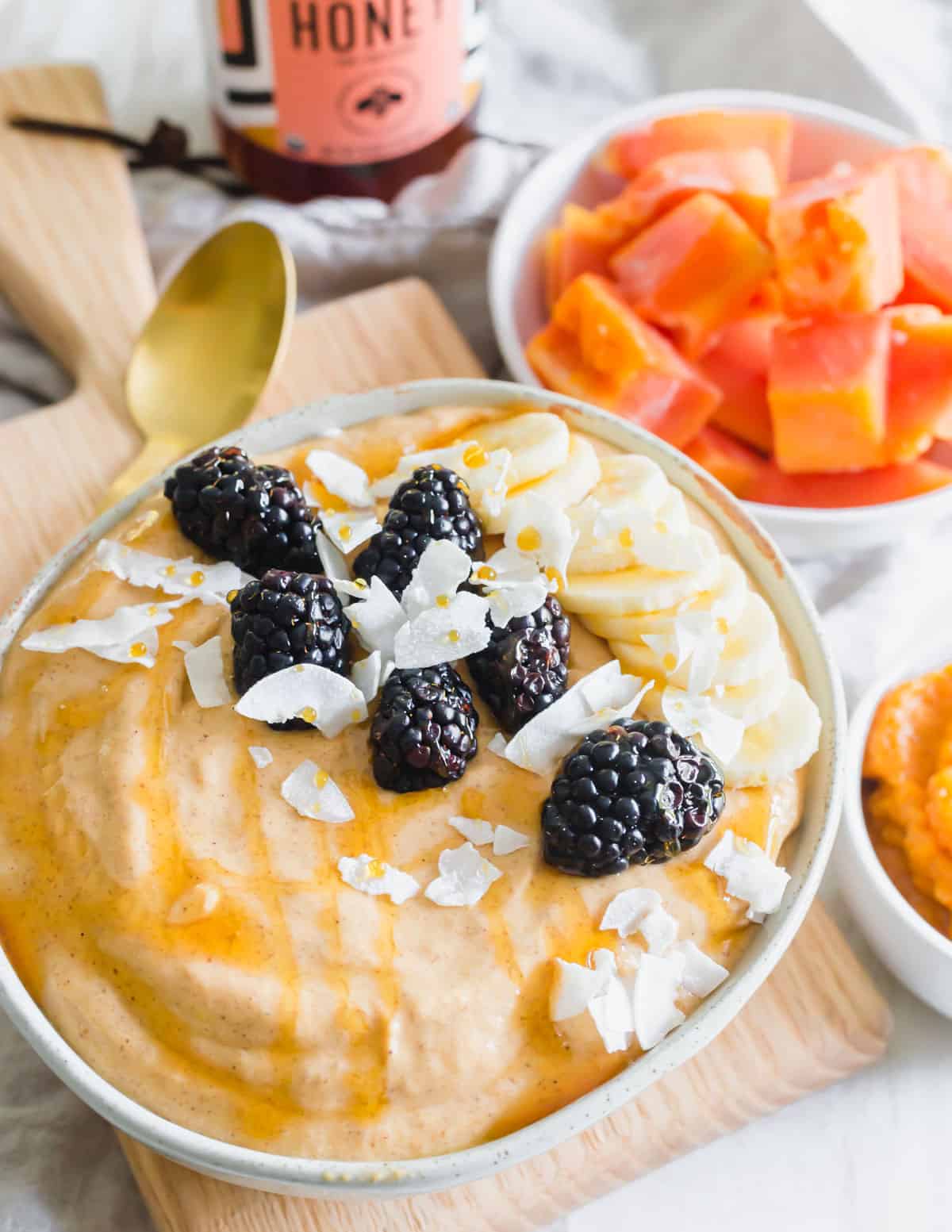 Pumpkin papaya smoothie bowl topped with blackberries, coconut flakes and raw honey.