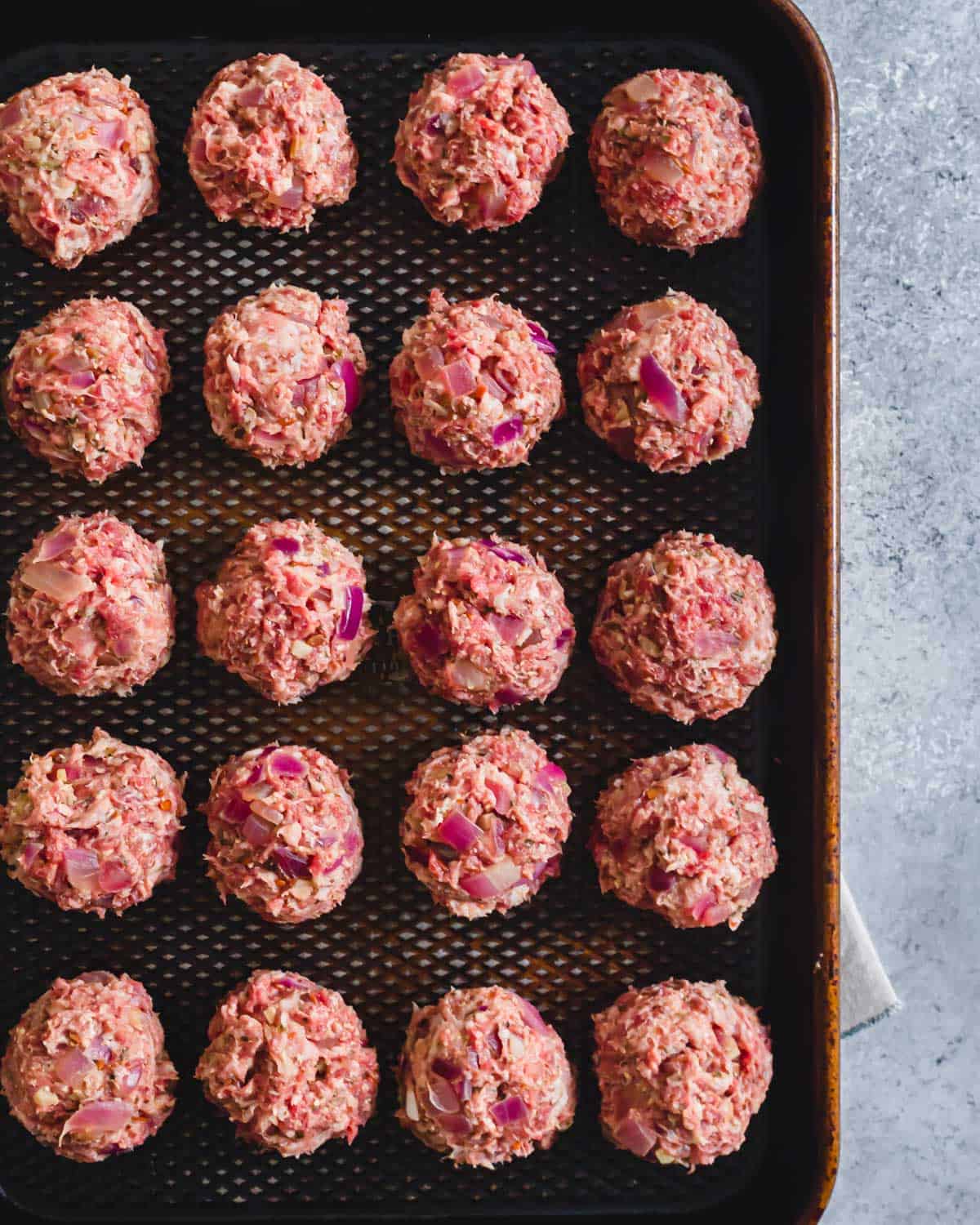 Prepared deer meat meatballs on a baking sheet.