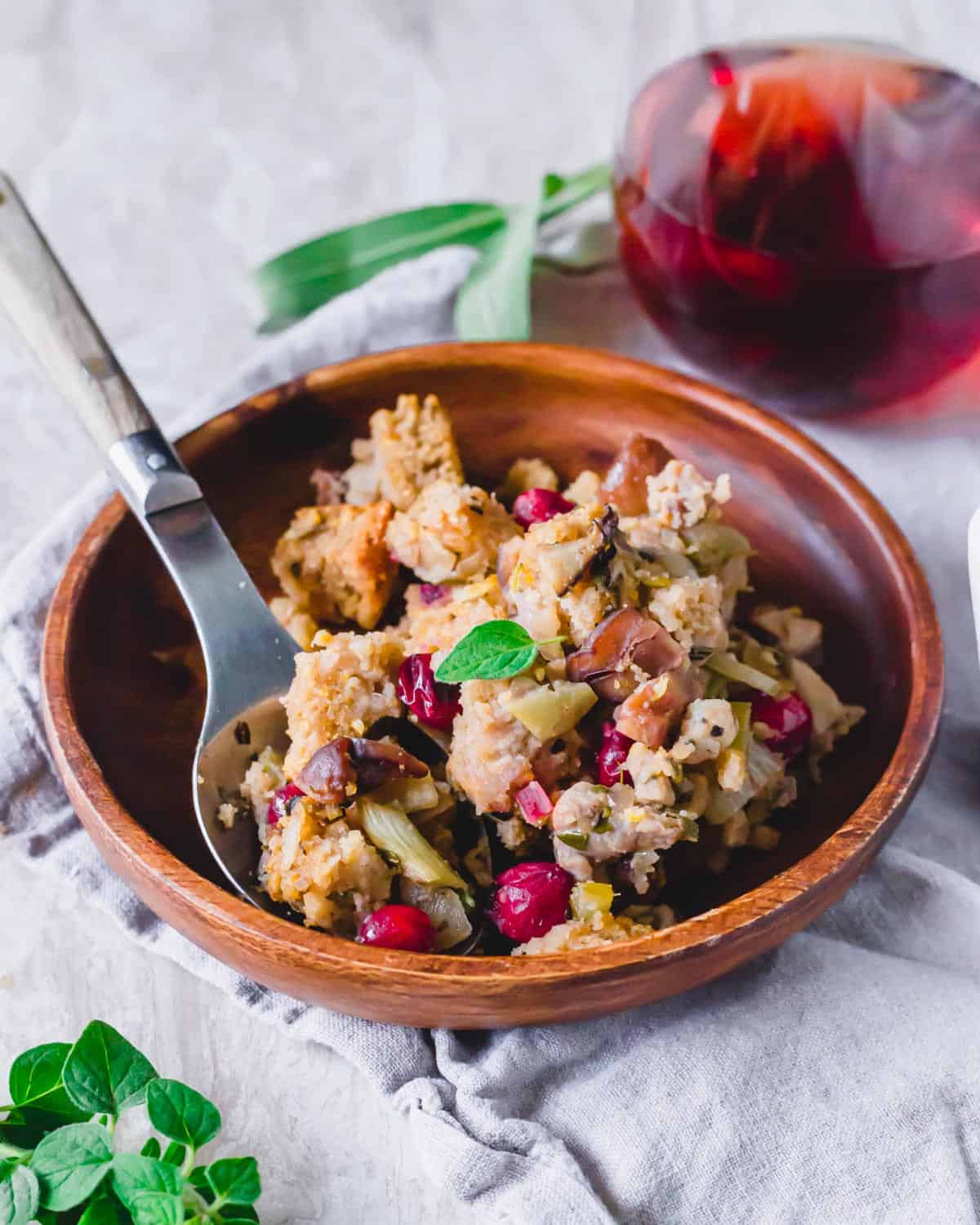 Holiday chestnut stuffing on a plate with cranberries and fresh herbs.