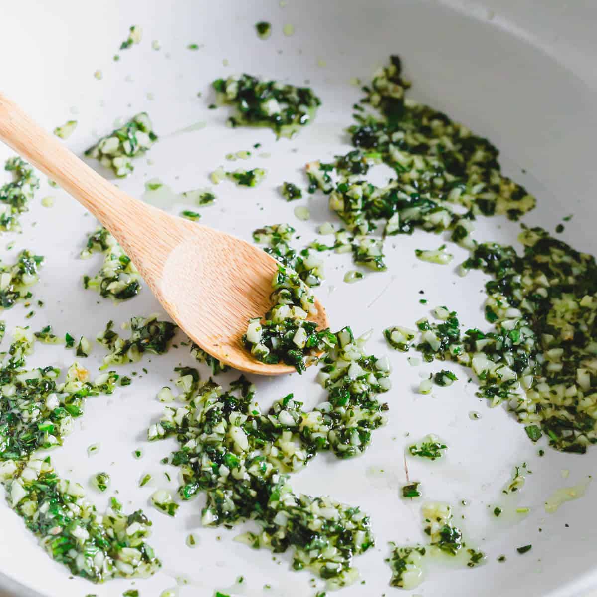 Minced herbs and garlic with melted butter in a pan.