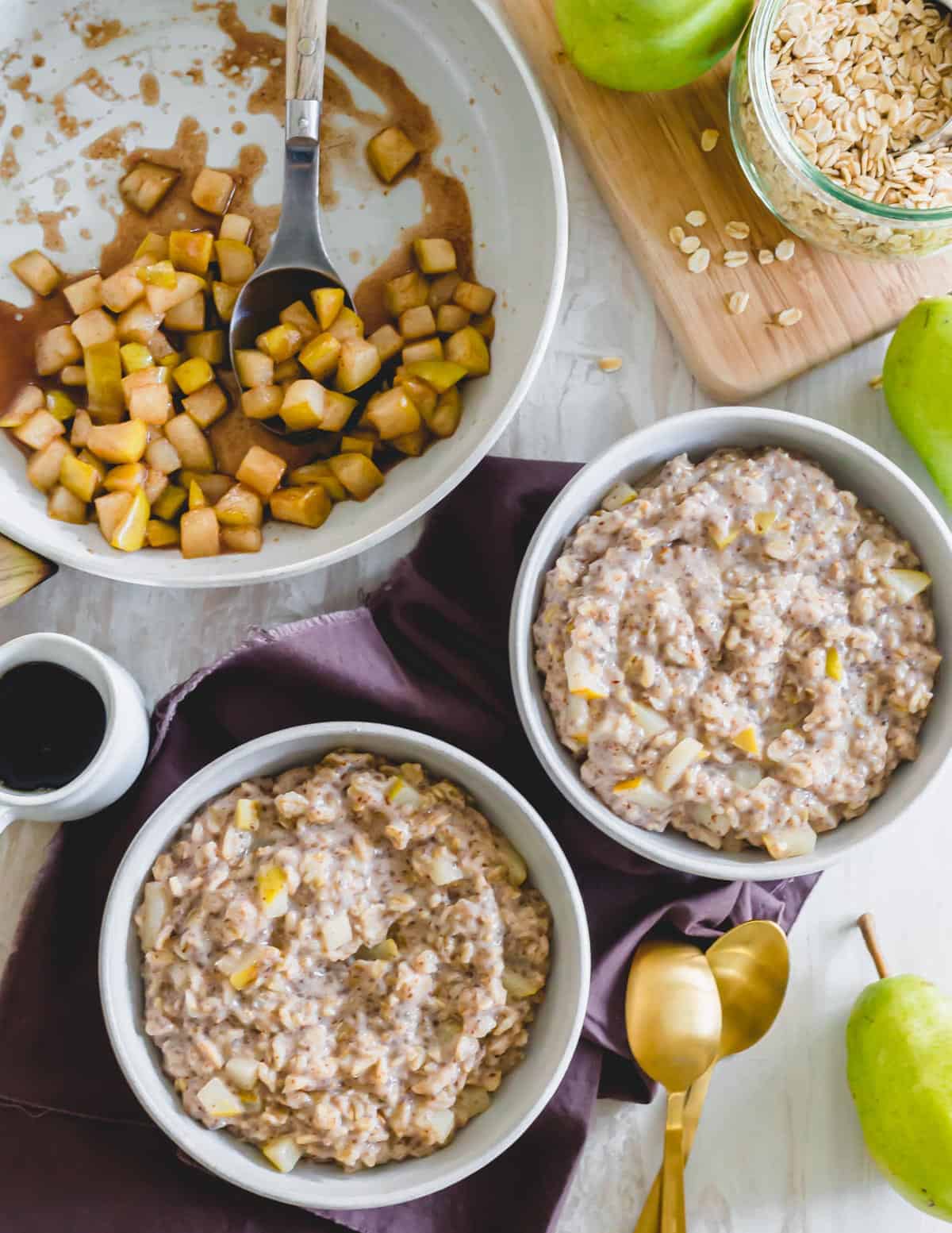 Oatmeal in bowls with caramelized spiced pears in a skillet.