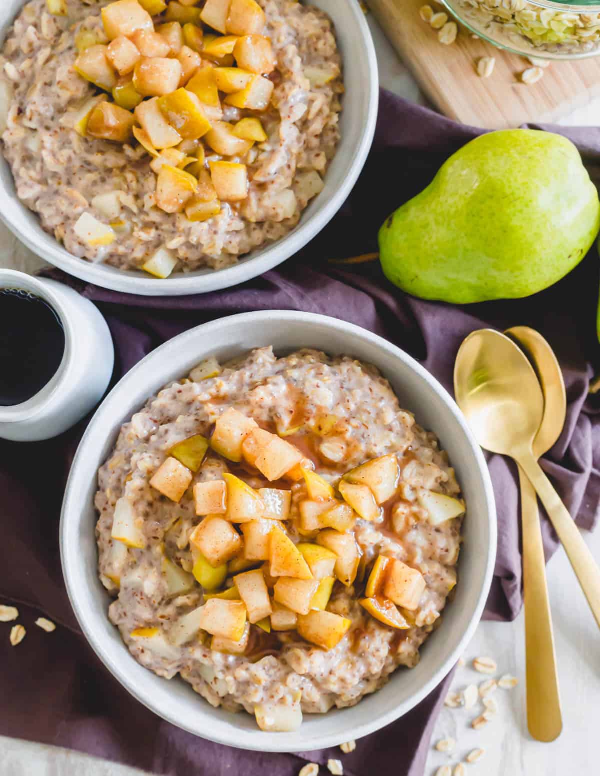 Cinnamon spiced pear oatmeal in a bowl with maple syrup.
