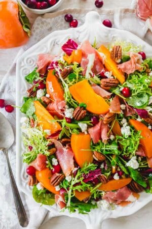 Persimmon salad with prosciutto, cranberries, goat cheese and pecans.
