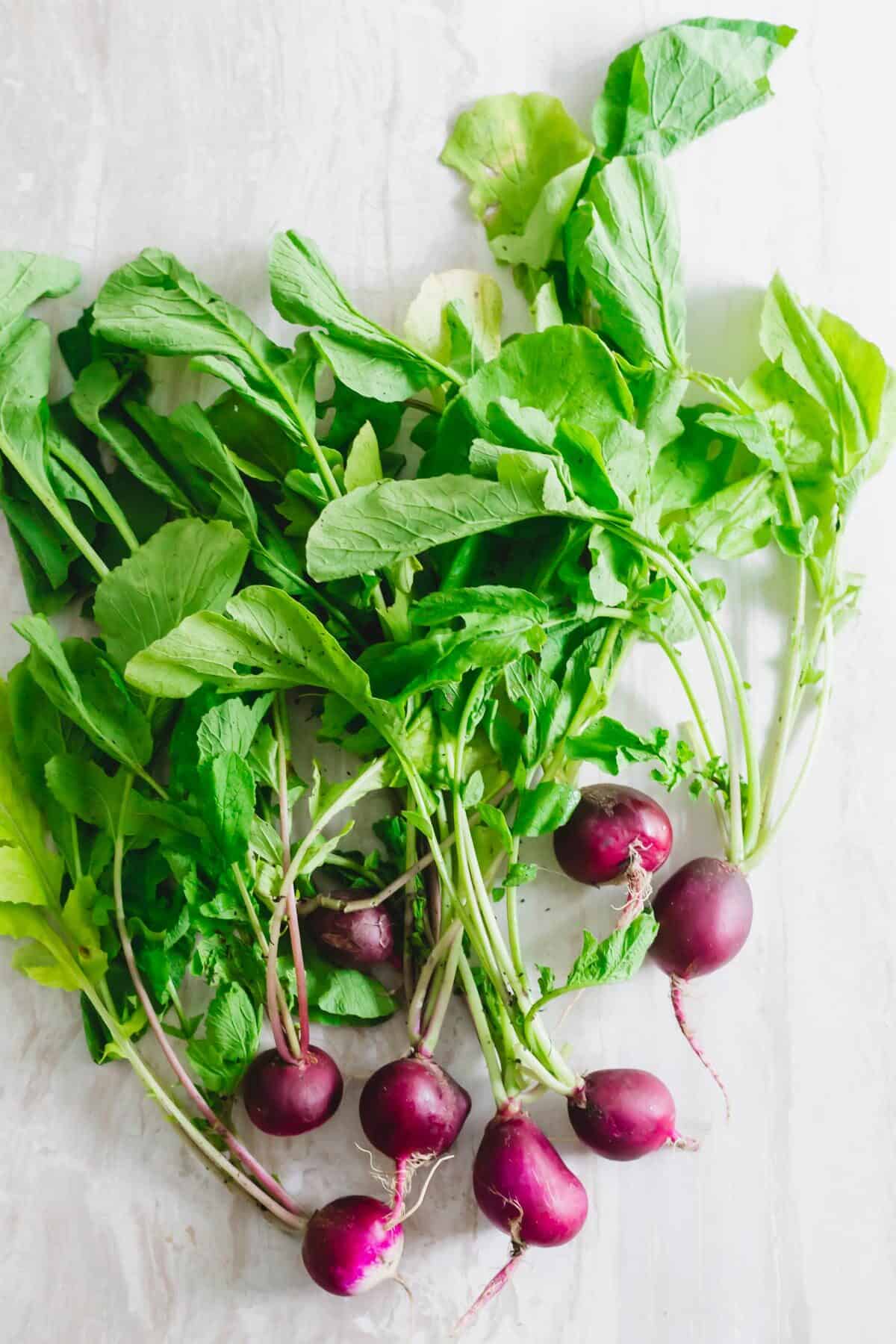 Bunch of radishes with greens attached.