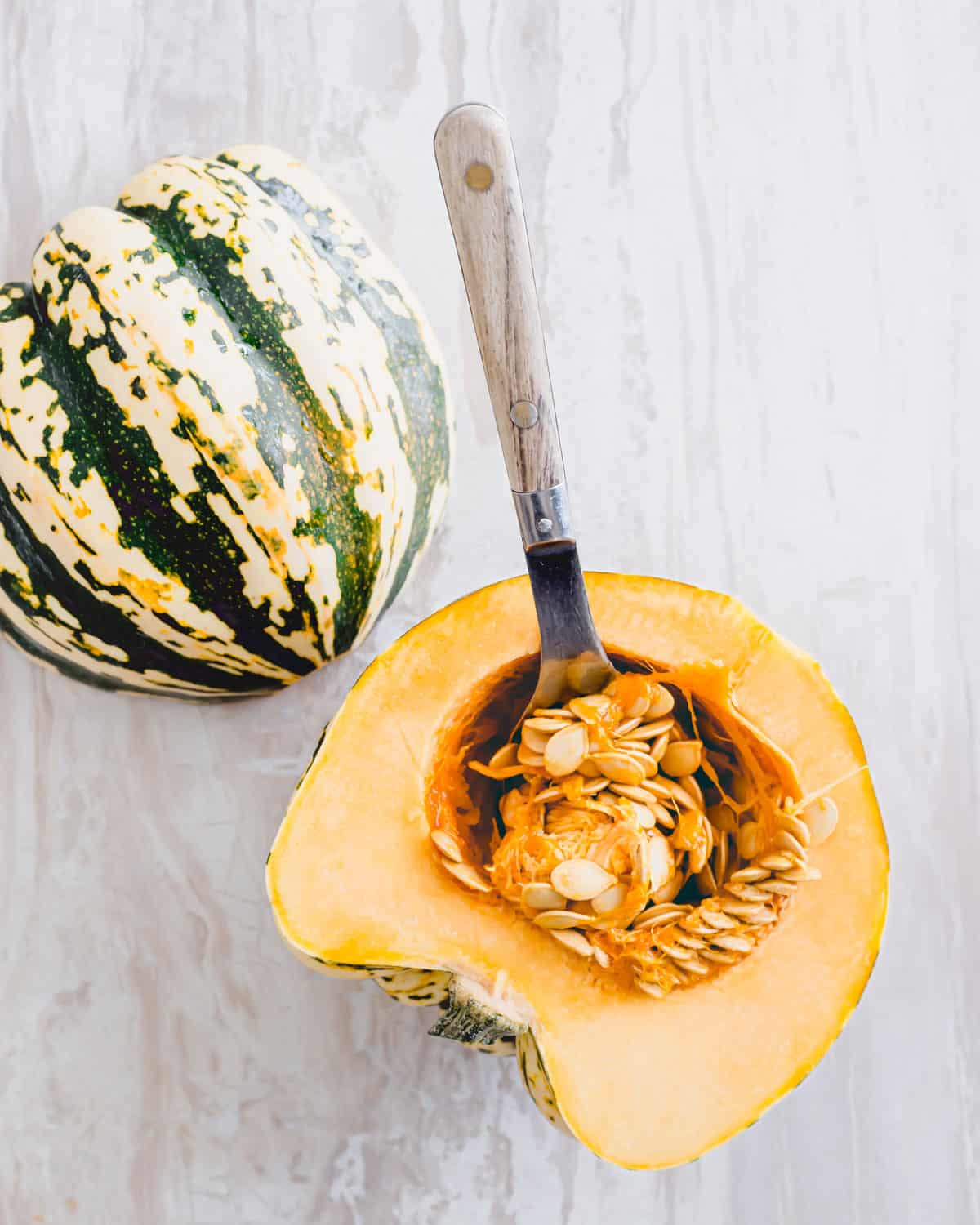 Sweet dumpling squash cut in half with seeds intact.