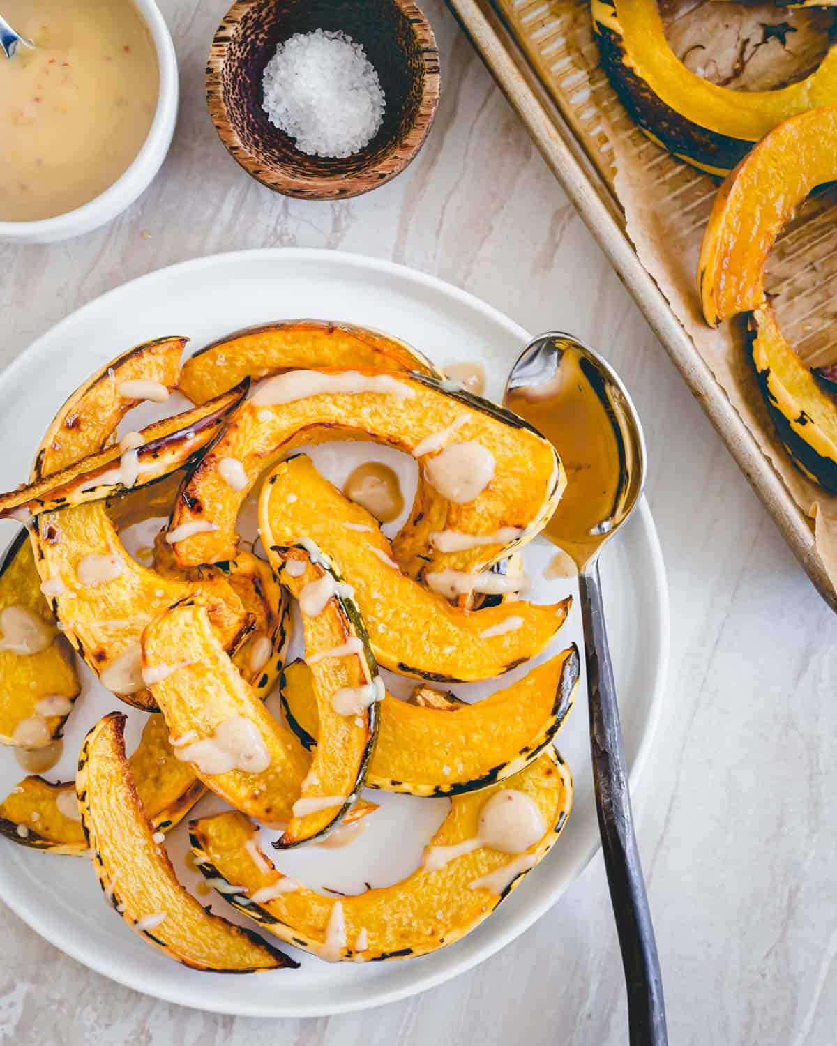 Perfectly roasted sweet dumpling squash on a plate served with a tahini maple sauce.