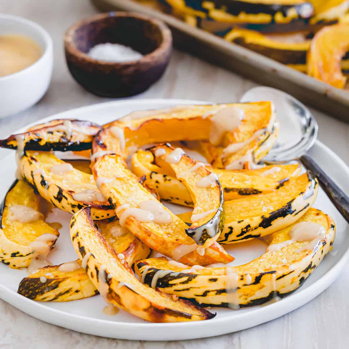 Fork tender sweet dumpling squash roasted in the oven and served with a maple dijon tahini sauce to dip or drizzle on top.