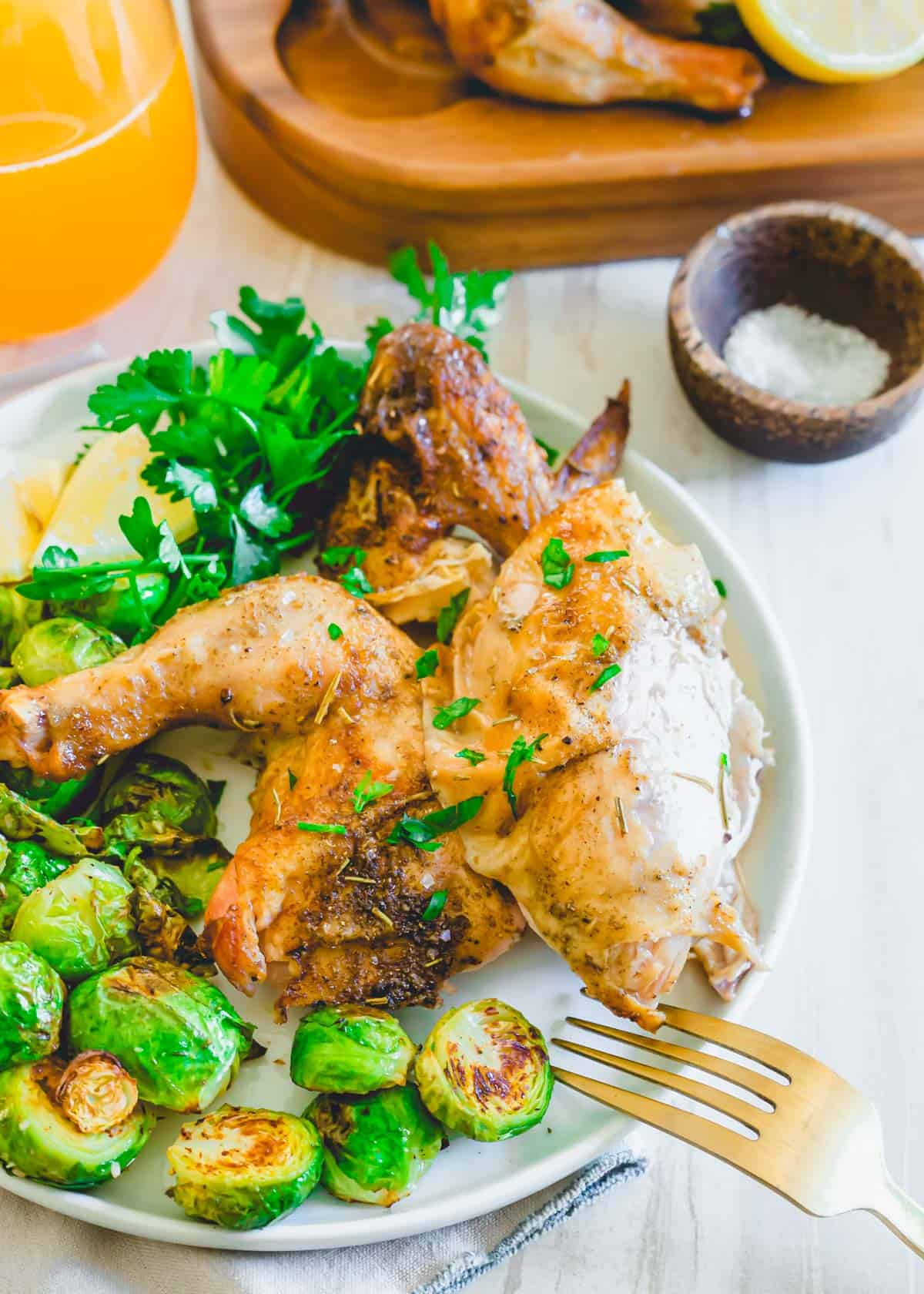 Air fried Cornish hen breast and leg on a plate with fresh parsley.