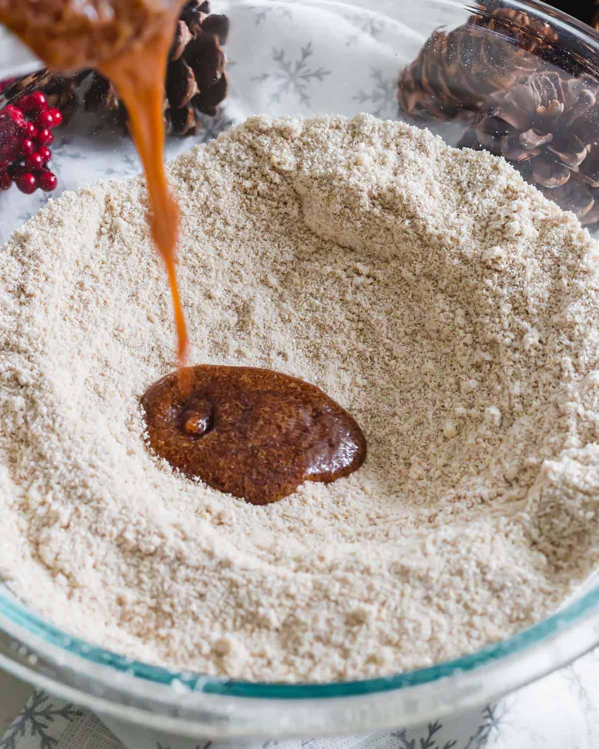 Oat flour and almond flour in a bowl with molasses to make gingerbread waffles.