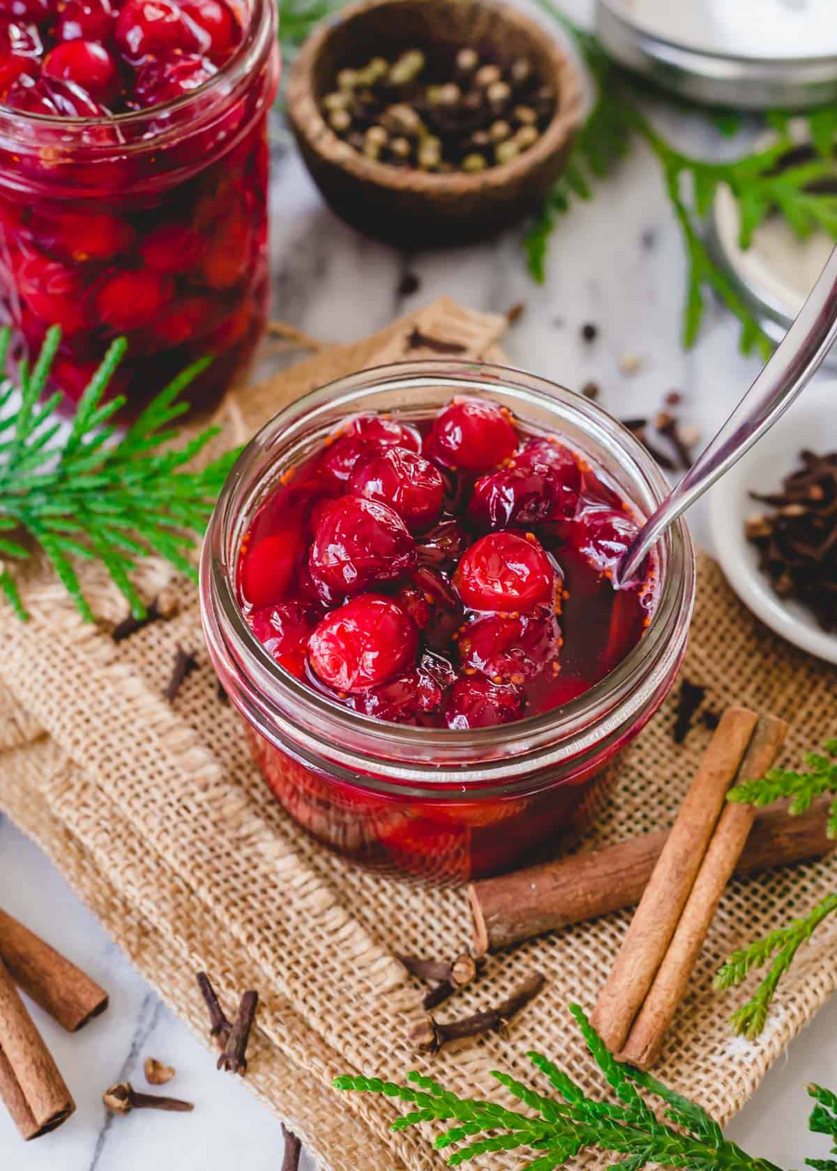 Pickled cranberries in a glass jar with spoon.