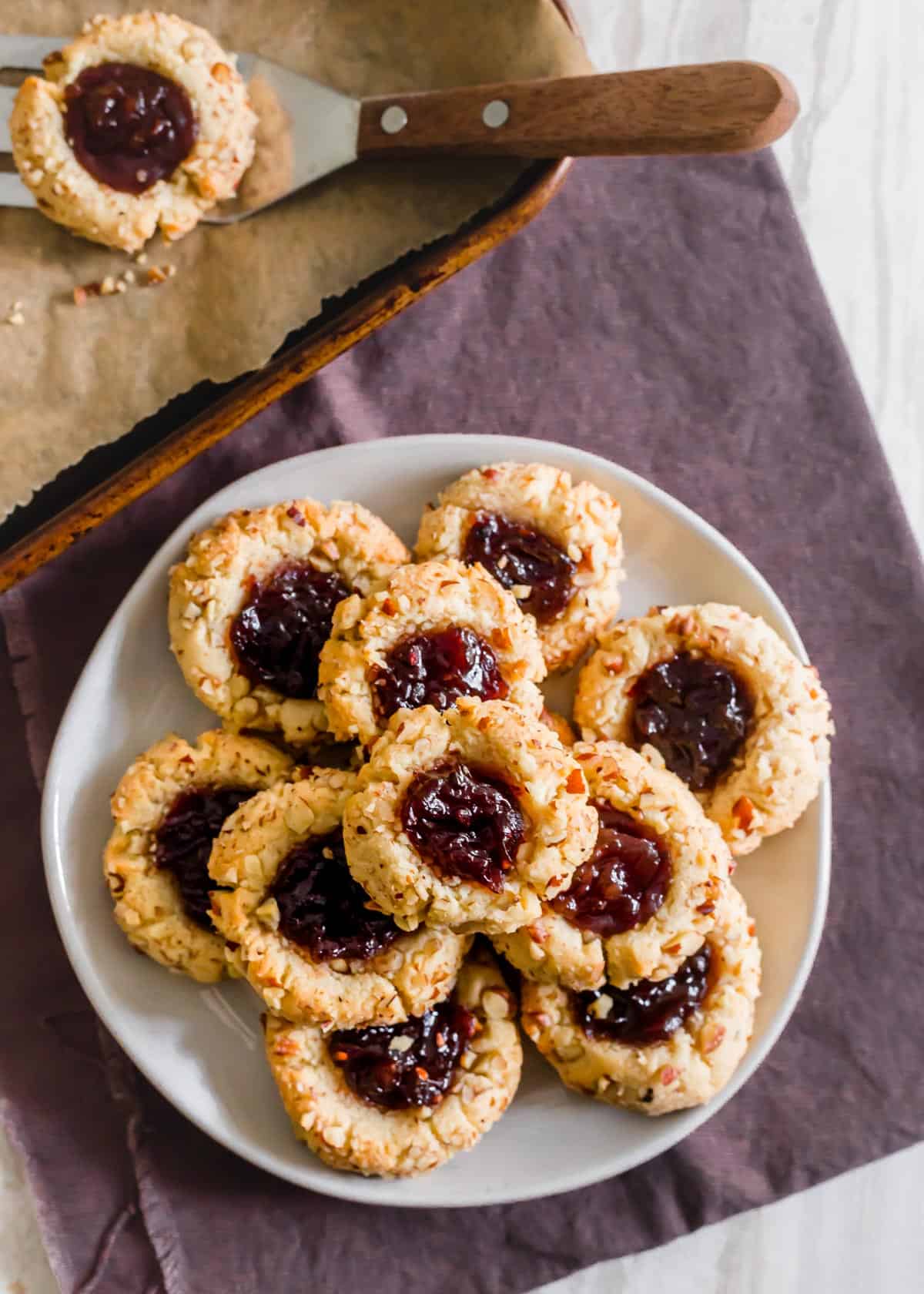 Plate of almond flour vegan thumbprint cookies with raspberry jam.