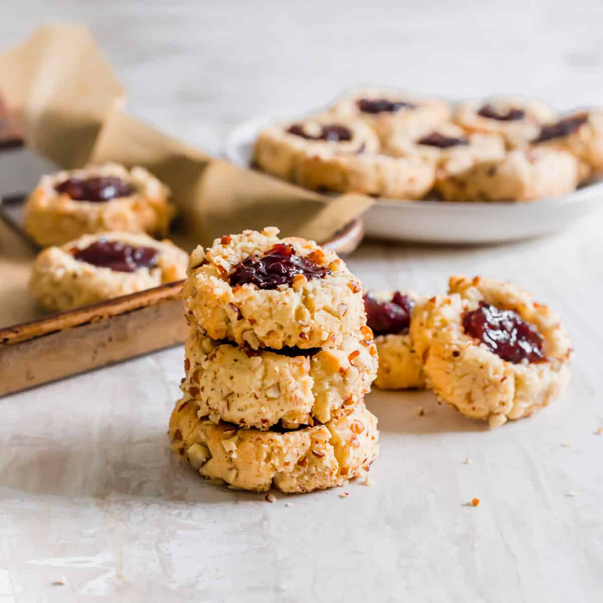 Pecan crusted vegan thumbprint cookies stacked on a table surface.