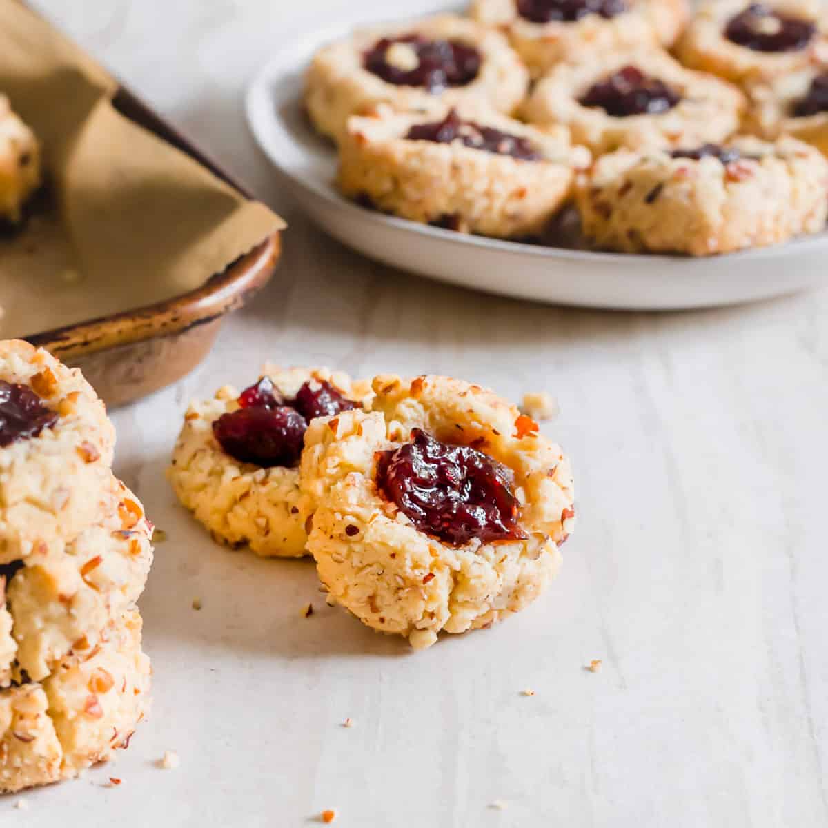 Vegan gluten-free thumbprint cookies with raspberry jam and chopped pecans.