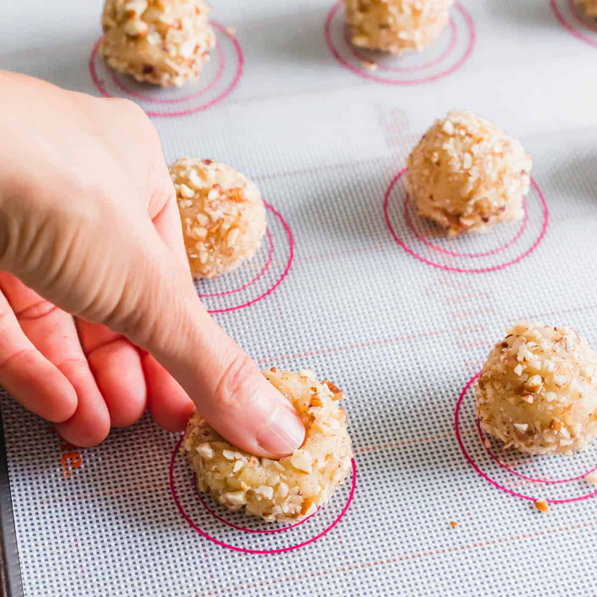 Making "thumbprint" in vegan thumbprints on baking sheet.