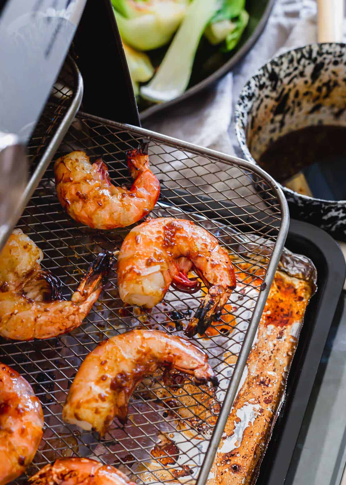 Air fryer frozen shrimp on tray of air fryer.