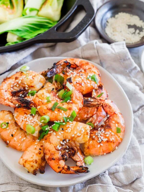Air fried frozen shrimp on a white plate garnished with green onion.