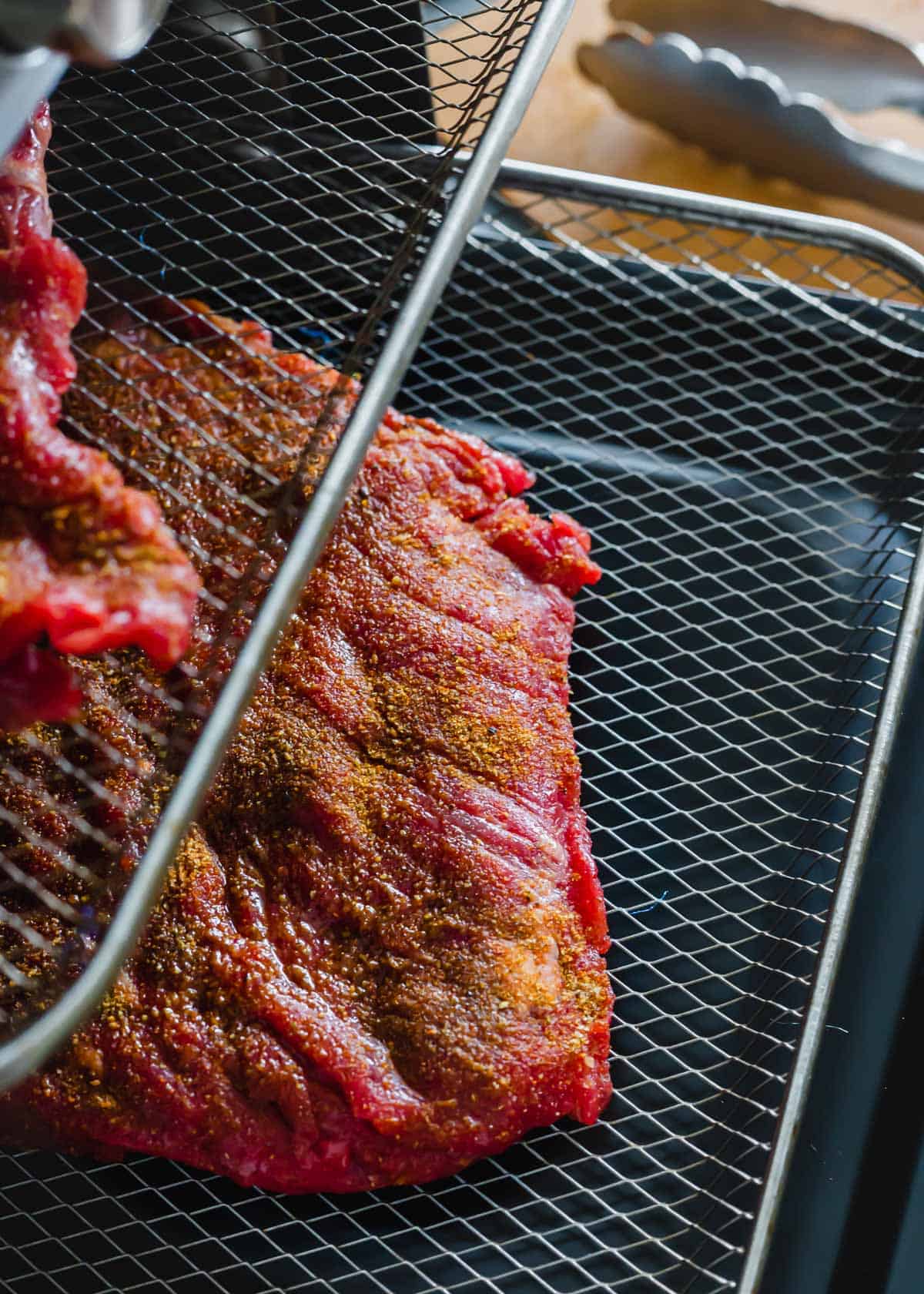 Seasoned skirt steak on trays in an air fryer oven.