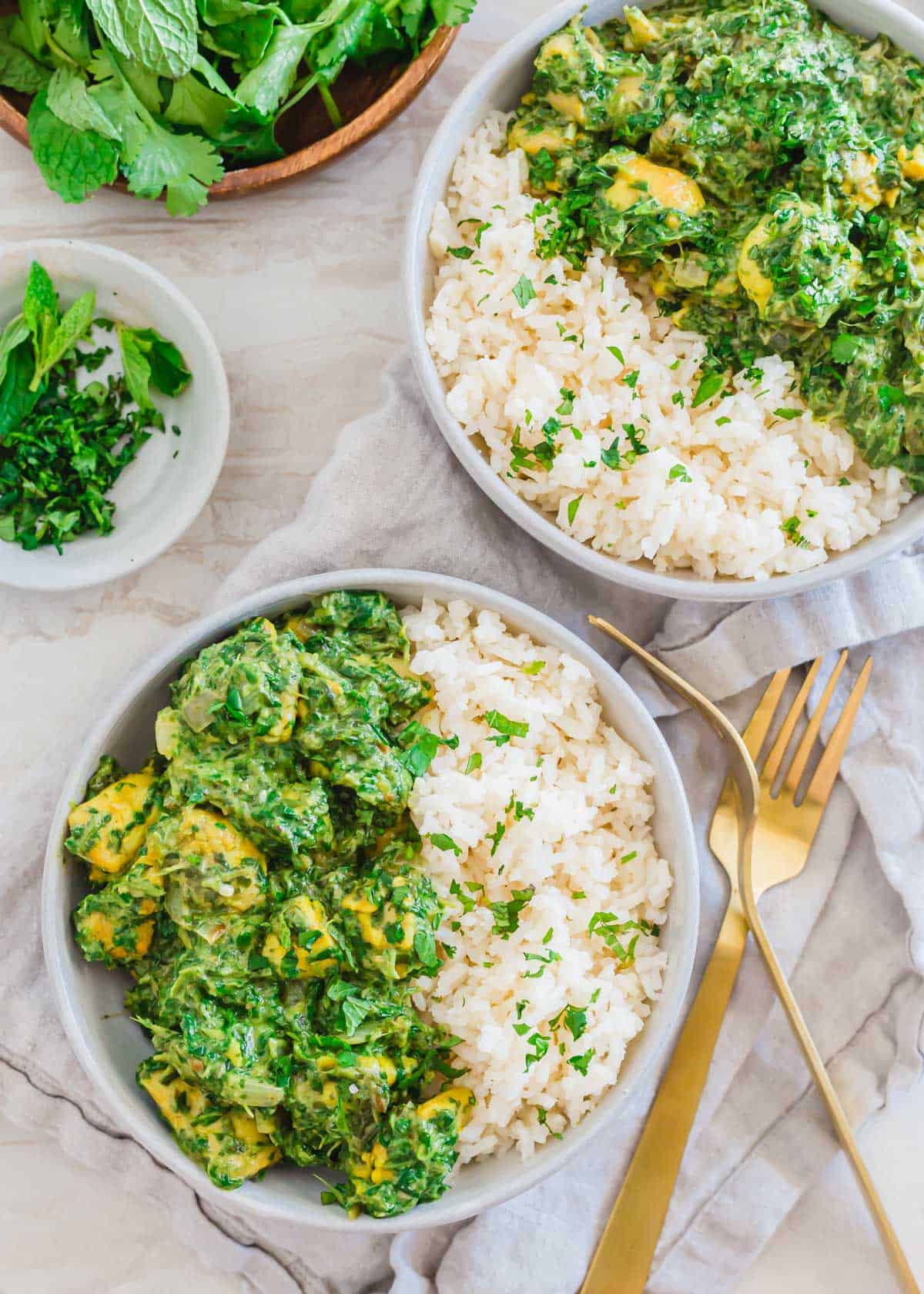 Chicken saag curry recipe served with white rice in bowls with forks and napkin.