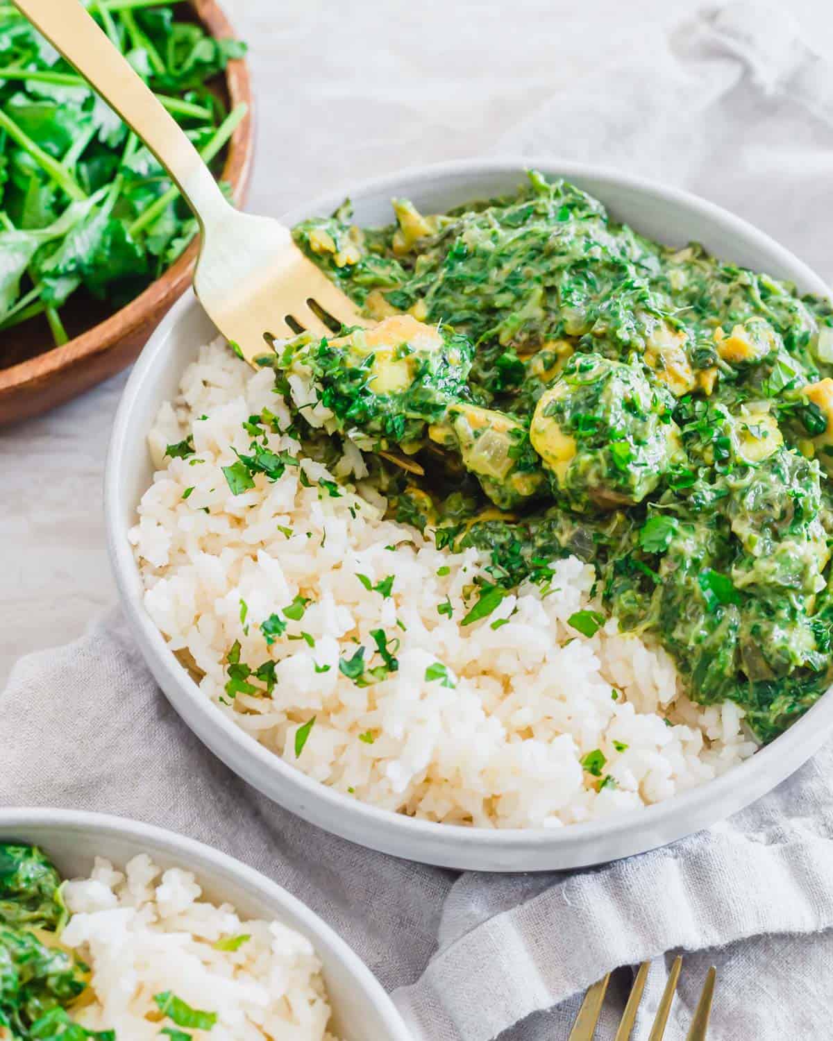 Easy chicken saag recipe in a serving bowl with rice and a fork.
