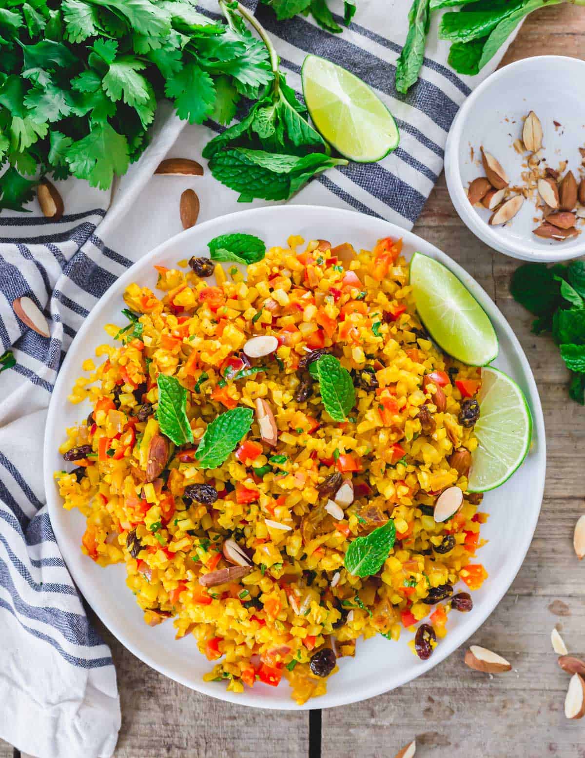 Overhead shot of curry cauliflower rice recipe on white plate with kitchen towel.