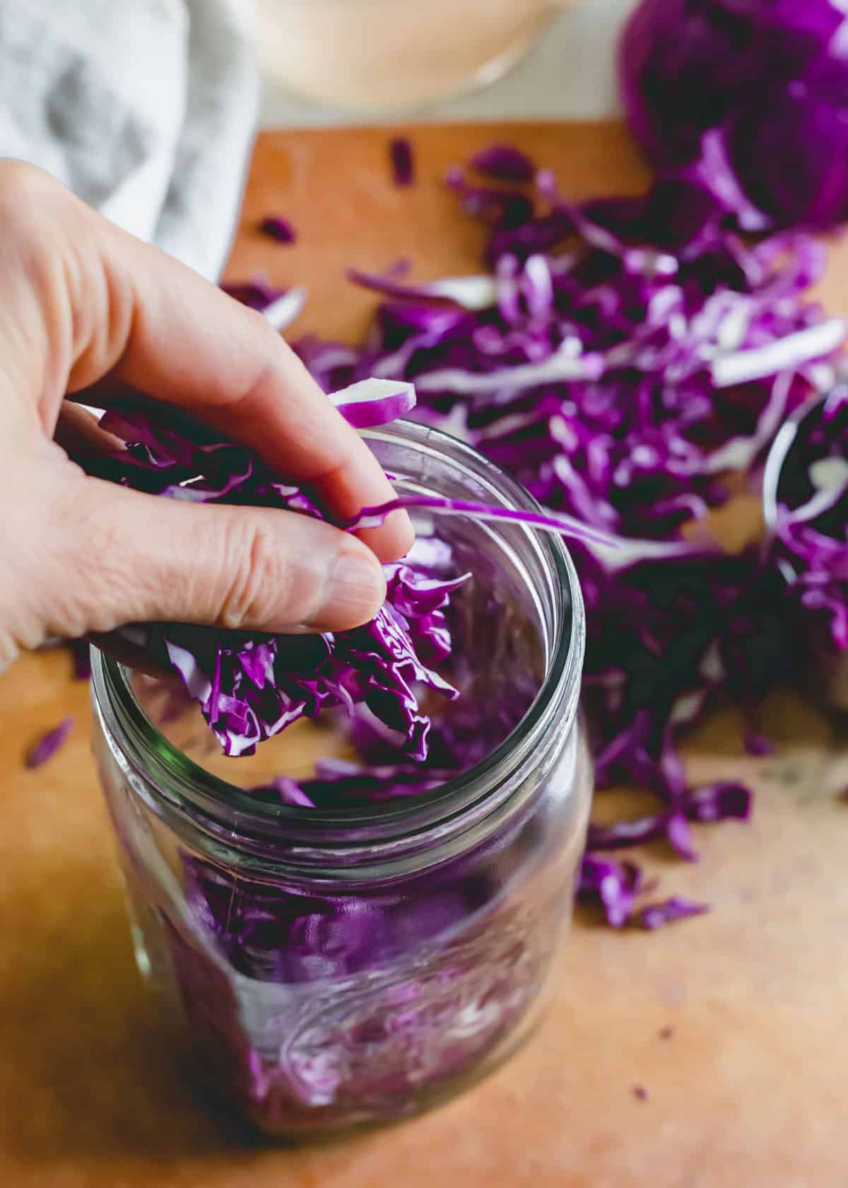 Adding shredded purple cabbage to a mason jar.