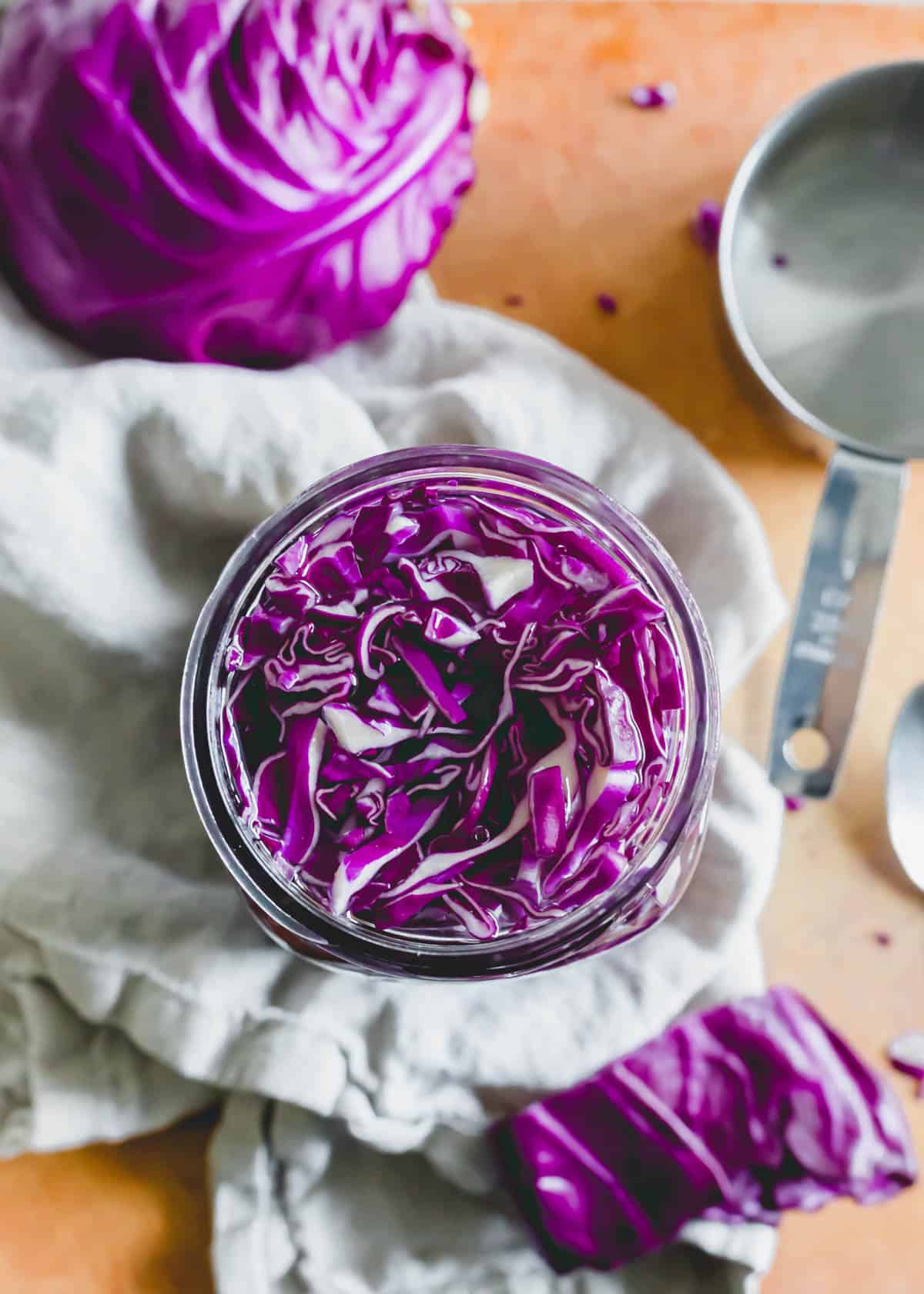 Top down view of glass mason jar filled with shredded red cabbage and salt water brine.