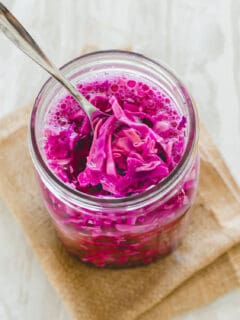 Red cabbage sauerkraut in a jar with a spoon.