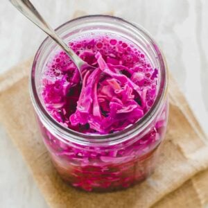 Red cabbage sauerkraut in a jar with a spoon.