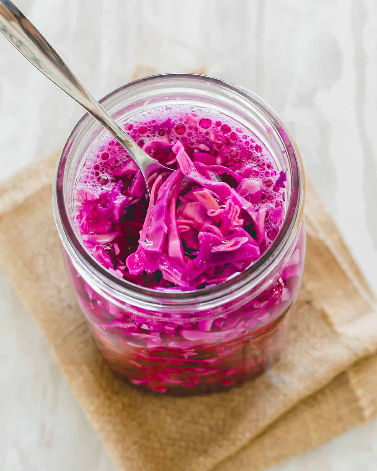 Red cabbage sauerkraut in a jar with a spoon.